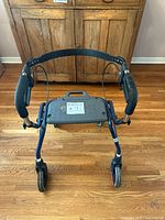 Front view of blue Dolomite Legacy rollator walker showing seat, wheels and folding strap