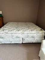 Full view of King Koil king mattress on split boxspring with metal frame base