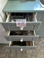 Three kitchen drawers containing flatware, utensils and folded linens