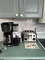 Ninja coffee system, Cuisinart toaster and manuals on countertop