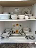 Cabinet view showing top, middle, bottom shelves with various white china and sunflower pieces