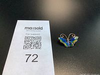 Front view of enamel butterfly brooch beside lot number card