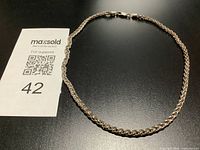 Full view of rope chain necklace beside reference card