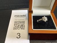 Ring in open presentation box next to lot card