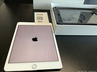 iPad powered on with Apple logo beside boxed OtterBox case