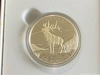 Reverse side of coin showing elk and $100 denomination