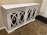 Front view of white wood cabinet with decorative doors