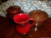 Group shot showing both brown crocks with lids and the red pitcher