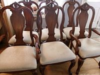 Front view of five chairs showing carved wood frames and upholstered seats
