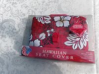 Front of sealed package showing red Hawaiian floral seat cover and branding