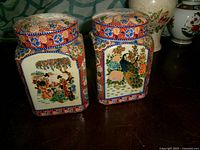 Front view of two square multicolor ginger jars with lids
