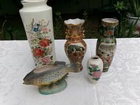 Front view of five vases and ceramic fish figurine displayed on table