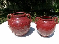 Two red glazed ceramic garden pots on table outdoors