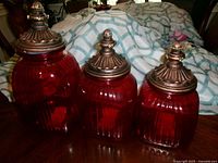 Three red glass canisters with lids