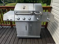 Full view of closed grill showing stainless exterior, side shelves, control panel and cabinet