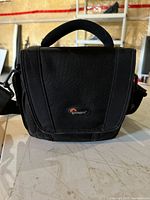 Front view of Lowepro camera bag showing logo, flap, handle, shoulder strap
