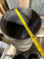 stack of large diameter black plastic pots with tape showing ~12 in.