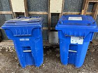 Front view of two blue recycling carts with lids closed, showing serial marking and condition