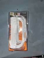 Front view of sealed blister pack showing white patio door handle and included hardware