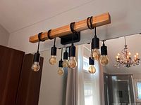 Front view of installed 5-light wood and black metal vanity fixture