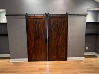 Front view of both dark stained barn doors installed on black metal track