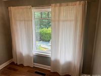 Two sheer curtain panels hung on rod in window alcove