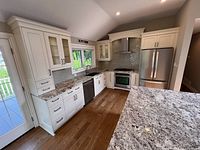 Overall view showing left run of cabinets, granite top, sink, drawers, glass uppers