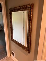 Front view of rectangular gold-tone ornate framed mirror hanging on wall