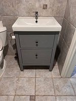 Front view of grey two-drawer vanity with white sink and faucet
