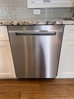 Front view of stainless Whirlpool dishwasher installed under counter