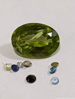 Group view showing large oval green gemstone and seven smaller assorted stones