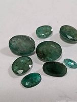 group of eight loose oval faceted emeralds, varying sizes