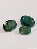 Three oval emerald gemstones on white background