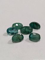 Six oval emerald gemstones on white background