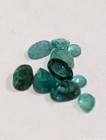 Group of loose faceted emeralds on white background