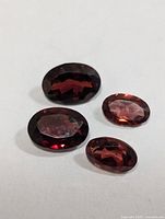 Four oval faceted garnet stones on white background