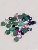 assortment of loose gemstones spread on white surface
