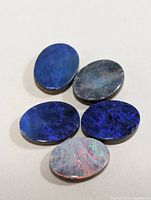 Five oval opal cabochons on neutral background