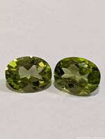 Front view of two oval peridots showing color and cut