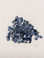 Pile of loose blue faceted sapphires on neutral background