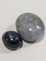 Two loose oval cabochon star sapphires side by side on white background