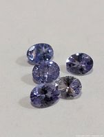 Five oval tanzanite gemstones on white background