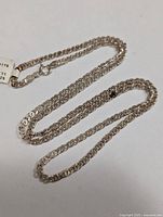 Full view of silver chain coiled, showing overall length and shine