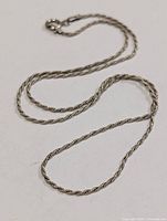Full view of twisted rope silver chain laid flat
