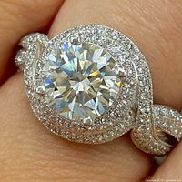 Close-up of ring on finger showing center moissanite, CZ halo, twist shank