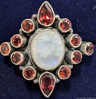 Front view showing oval moonstone and surrounding faceted garnets