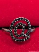 Front view of silver ring featuring @ symbol set with black onyx stones