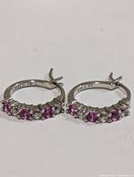 Pair of sterling silver hoop earrings showing front view of pink and clear stones, 925 stamp visible