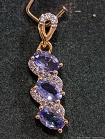 Front view of silver pendant with three oval tanzanite stones and clear accents