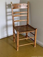 Front angled view of wooden ladder-back chair showing woven leather seat and overall form